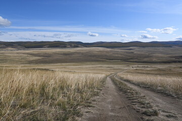 A long and crooked road through the steppe with a blue sky