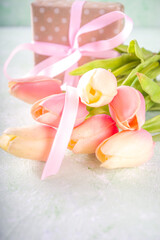 Tulips bouquet with giftSpringtime pink tulips bouquet with gift for Valentine day, Mothers Day or Easter concept. Light green concrete background copy space