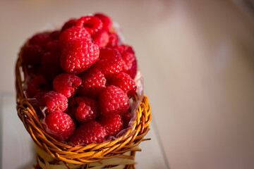 Ripe raspberry berries are folded into a wicker basket