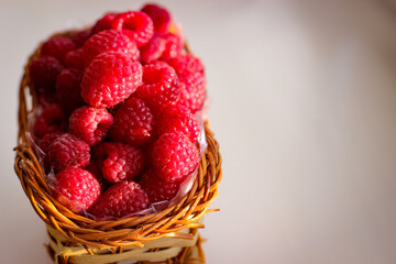 Ripe raspberry berries are folded into a wicker basket