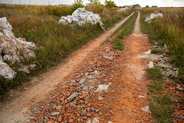 Dirt road and piles of broken bricks around. Construction waste concept with copy space