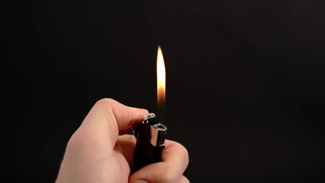 Ignition of a lighter on black background with a hand and let the fire flame burn