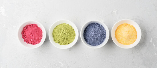 Obraz na płótnie Canvas Bowls of multicolored matcha tea powder on a concrete background. Top view.