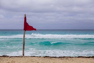 Red flag on the beach and waves in cancun Mexico