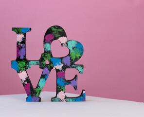 Love.  Colorful wooden word love on pink pastel background at front view
