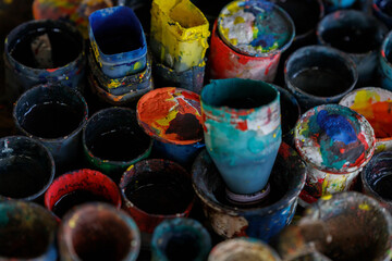 colorful used paint cans stand on the table creating an interesting and colorful texture