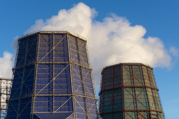 Smoking chimneys. Cooling towers release steam against the blue sky. Industrial landscape. Air...