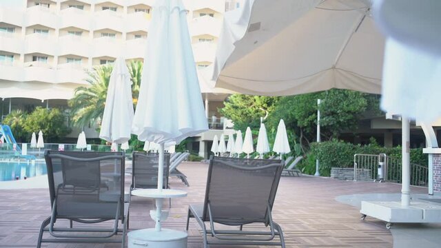 Empty hotel territory with white umbrella recliners and pool. Concept lockdown in tourist industry.