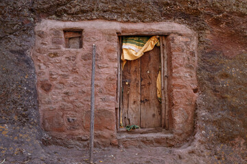 carved wooden door on a rock wall which is the monastery facade of an Ethiopian monastery