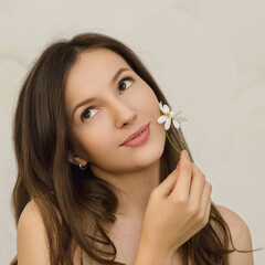 young beautiful woman brunette holds a chamomile near her face