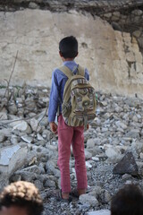 A sad Yemeni child stands on the rubble of his school destroyed by the war 