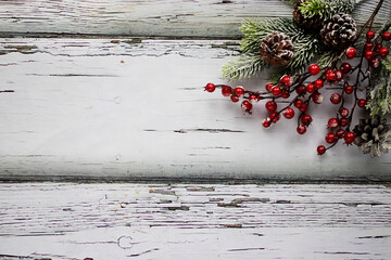 Decorative branches with red berries and white snow on old wooden  background. Copy space. Top view.