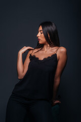Fototapeta premium Beautiful sexy woman with straight black hair looking aside and being isolated on a dark background