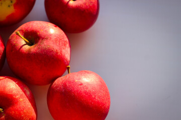 Fototapeta na wymiar Several ripe red apples stand on a white background illuminated by rays of the sun