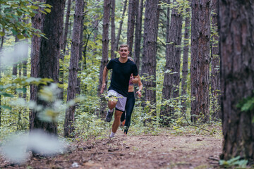 Obraz premium Strong male runner jogging for marathon on forest road