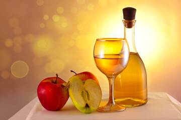 Apples, apple wine in a glass and in a bottle on a white sparkling background.