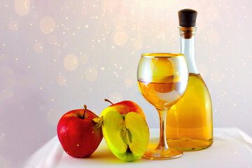 Apples, apple wine in a glass and in a bottle on a white sparkling background.