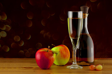 Apples, apple wine in a glass and in a bottle on a black sparkling background.