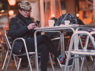 Fototapeta na wymiar Mujer joven paseando por las calles de una ciudad y tomando algo en la terraza de una cafeteria o bar