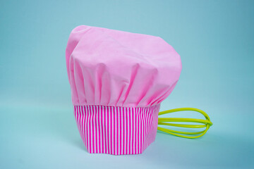 pink chef hat with a whisk on blue background