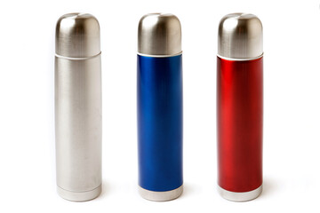 Three stainless steel thermoses red, blue and metal isolated on white background. Vacuum flask or bottle for hot tea or coffee for traveling or camping. 