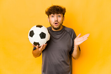 Young soccer player indian man surprised and shocked.