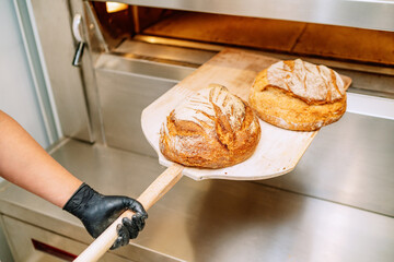 Baker putting bread in the bakery oven cowering on the floor of the bakery