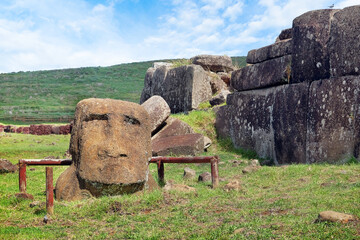 Moai head and stone structure at the ceremonial center of Vinapu, on Easer Island - Rapa Nui, against a blue sky covered by white clouds.
