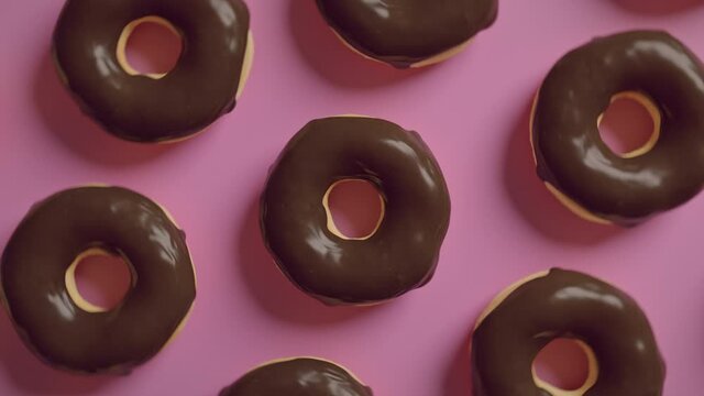 Chocolate frosting donuts on a pink background
