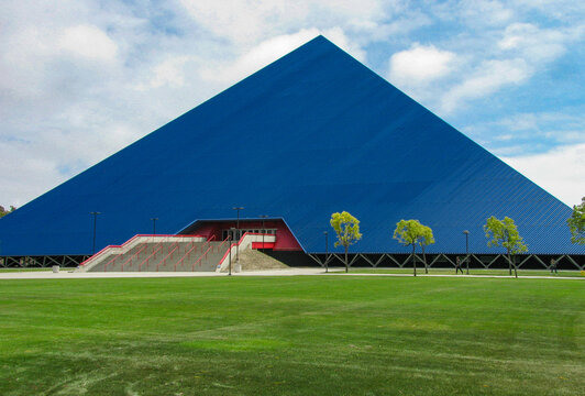 Long Beach, California USA - May 11, 2018: The blue Walter Pyramid sports arena north face on the campus of the state University, set back from Atherton Street by a wide lawn of green grass.