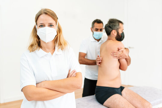 Portrait Of A Female Physiotherapist With A Mask And Crossed Arms In The Rehabilitation Clinic. Space For Text