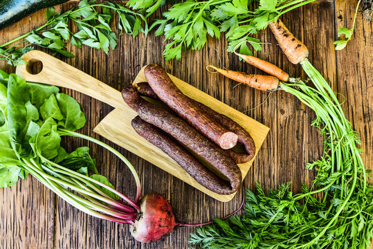 Sausage served on an oak board among vegetables from the home garden.