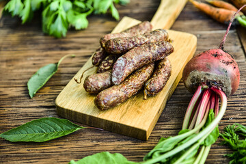 Sausage served on an oak board among vegetables from the home garden.