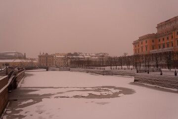 Fototapeta na wymiar Thin ice on the Moika River and a view of the Mikhailovsky Castle in St. Petersburg, snowy and traditionally gloomy December. Winter in St. Petersburg in Russia