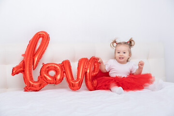 cute baby girl holds the inscription love from balloons on a white background.