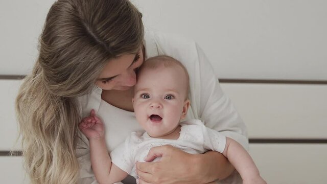 Little baby girl smiling and babbling looking at camera, spending time with mom