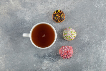 A white cup of tea with small delicious doughnuts