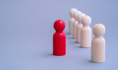 Red figure of a man made of wood, standing out from the crowd of. Different people. Unique human shape among light ones. Leadership, individuality and standing out of crowd concept. Human resource