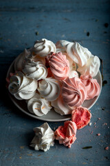 Pattern with delicate light white and pink meringue cookies on wooden background.