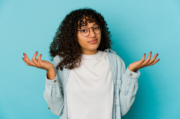 Young african american afro woman isolated doubting and shrugging shoulders in questioning gesture.