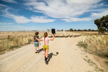 Children herding sheep on dusty dirt road in Australian outback