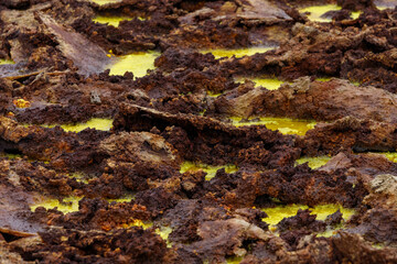 yellow and red stones in a volcanic crater that smokes and boils from the heat, they look like egg yolk with chocolate