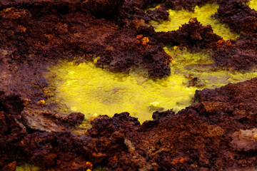 yellow and red stones in a volcanic crater that smokes and boils from the heat, they look like egg yolk with chocolate