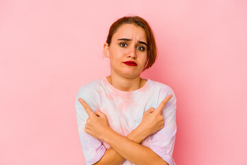Fototapeta premium Young arab mixed race woman points sideways, is trying to choose between two options.