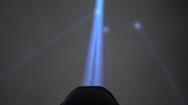 Close up on the searchlight at night. The light is very strong and illuminates the night sky.