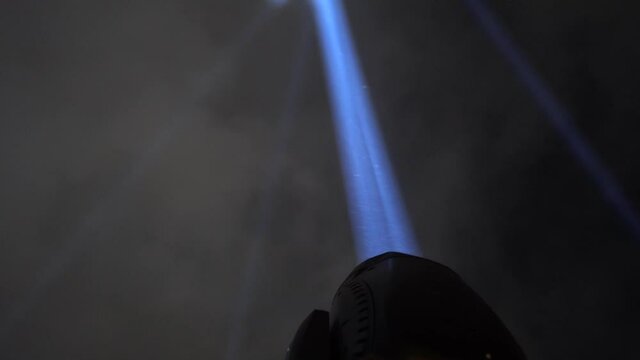 Close up on the searchlight at night. The light is very strong and illuminates the night sky.