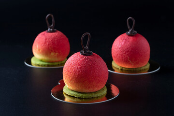 Three mousse desserts in the form of Christmas balls on a dark background.