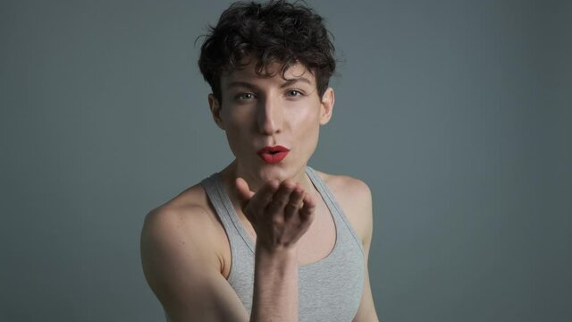 Portrait of handsome transgender man with makeup sending air kiss to camera. Medium shot. Masculine and feminine characteristics in one person. Gender identity concept 4k