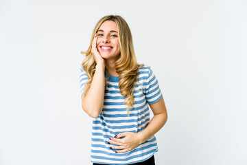 Young caucasian blonde woman laughs happily and has fun keeping hands on stomach.