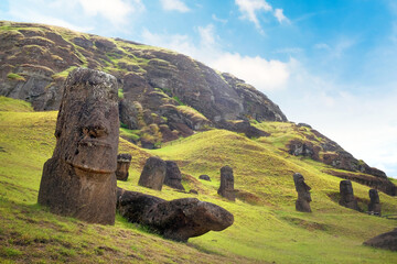 Moai on the slopes of the Rano Raraku Volcano, on Easer Island, against a blue sky covered by white...